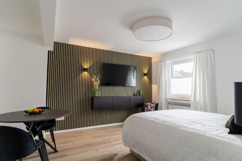 a bedroom with a bed and a table and a tv at Green Flat Düsseldorf First in Düsseldorf