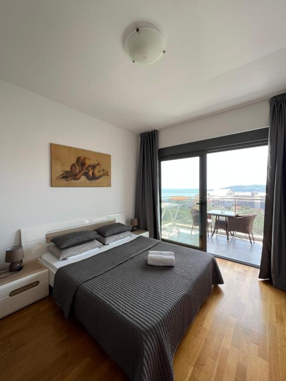Paradise Apartments Becici في بيشيشي: غرفة نوم بسرير كبير ونافذة كبيرة