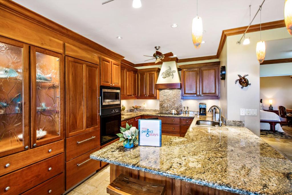 a kitchen with wooden cabinets and a counter top at Kapalua Golf Villa 18T 1&2 in Kahana