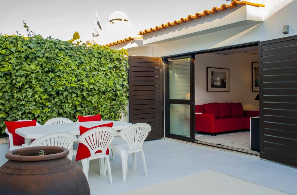 un patio con una mesa y sillas blancas y un sofá rojo en BmyGuest - Vilamoura Golf Villa, en Vilamoura