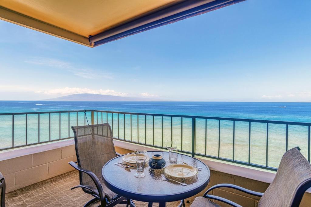 Una mesa en un balcón con vista al mar. en Maui Kai 801, en Kahana