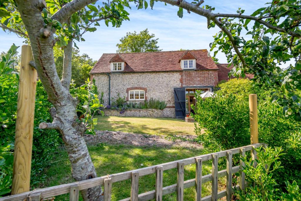 a stone house with a fence in front of it at Beachy Barn in Eastdean