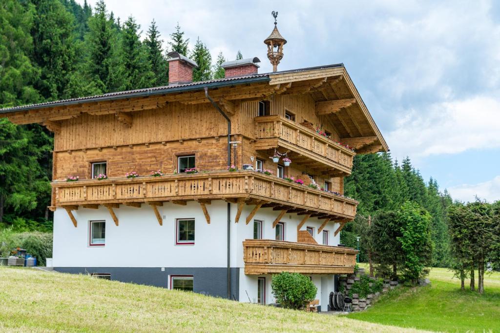 a house with a wooden roof on top of a hill at Kesselgrubs Apartements Ski & Badeglück in Eben im Pongau