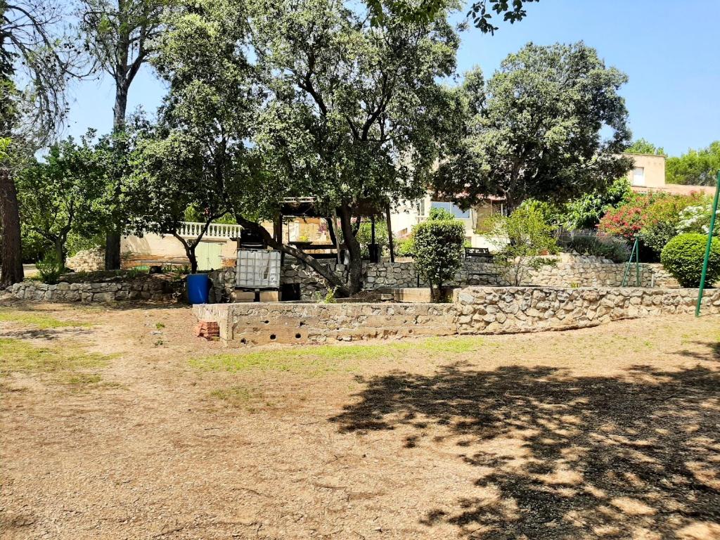 a yard with a stone retaining wall and trees at Villa de 2 chambres avec piscine privee jardin clos et wifi a Merindol in Mérindol