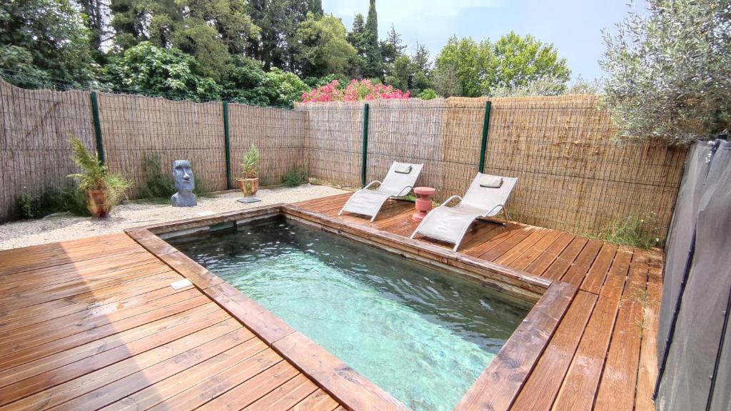 een zwembad met 2 stoelen en een houten terras bij Impression du Sud Gîte 2 in Saint-Rémy-de-Provence