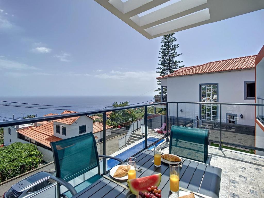 a balcony with a table and chairs with a view of the ocean at Casa Teixeira by Atlantic Holiday in Estreito da Calheta