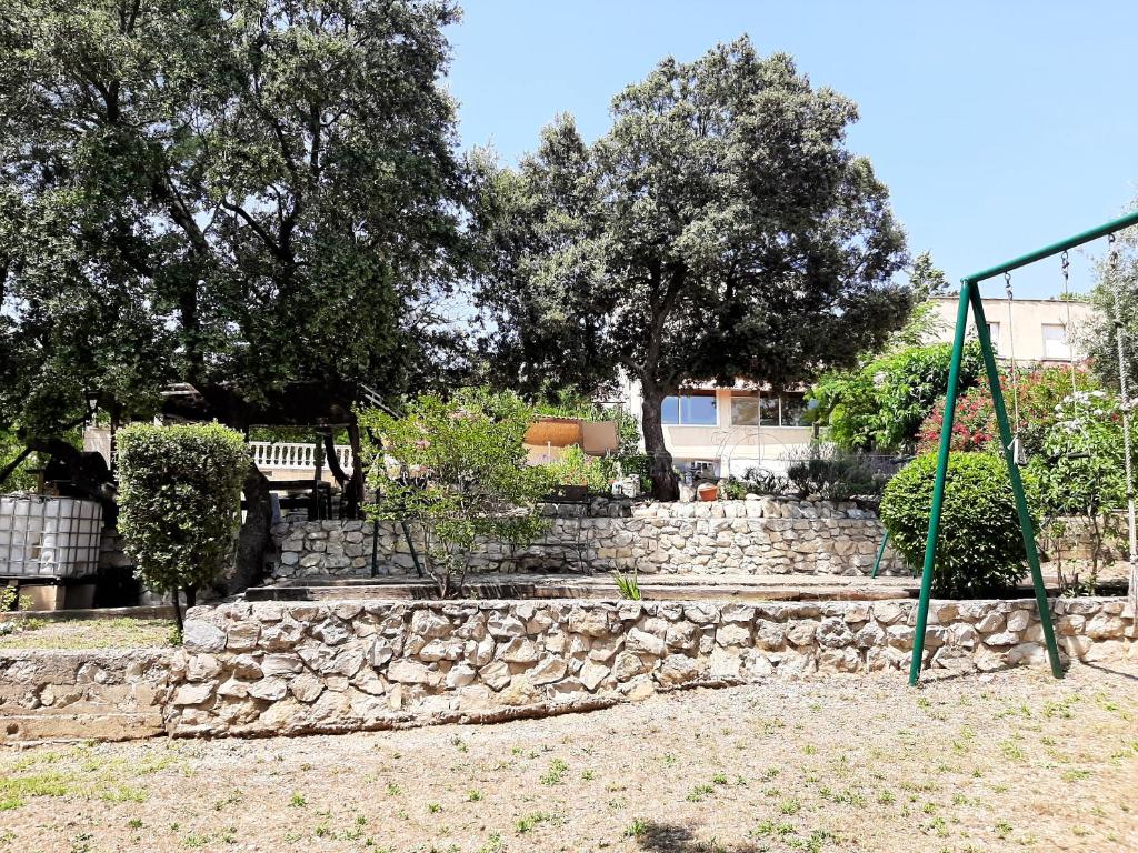 a stone wall and a swing in a park at Villa de 2 chambres avec piscine privee jardin clos et wifi a Merindol in Mérindol