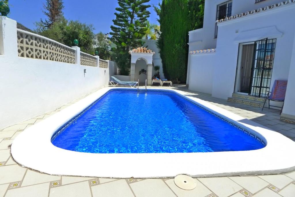 una piscina frente a una casa blanca en Villa Golondrinas - Private villa to sleep 6, en Nerja