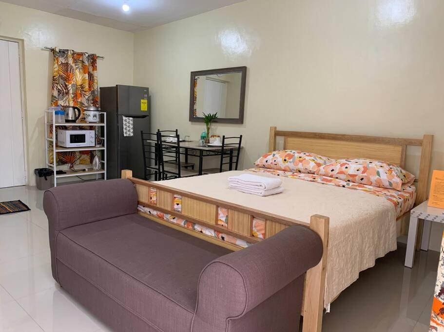 a bedroom with a large bed and a couch at A comfy retreat in the heart of Orani, Bataan in Orani