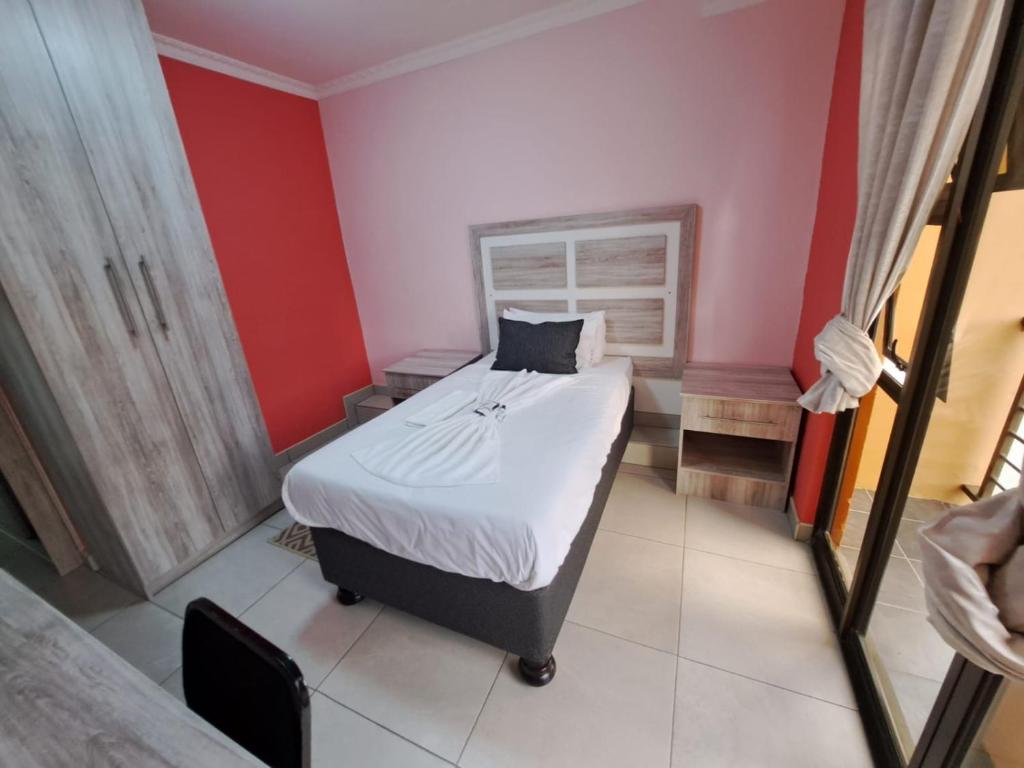 1 dormitorio con cama y pared roja en Jate Guest House, en Maseru