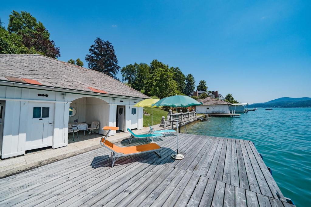 ein Dock mit zwei Stühlen und einem Regenschirm auf dem Wasser in der Unterkunft Villa Fernblick in Velden am Wörthersee