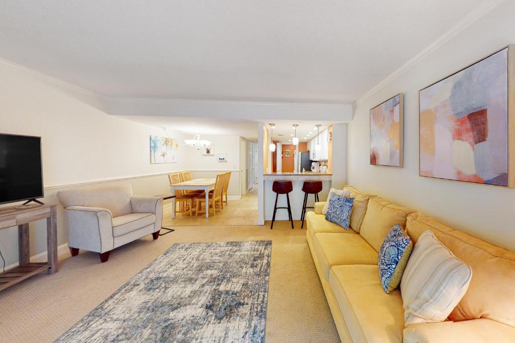een woonkamer met een gele bank en een televisie bij Hilton Head Beach Club Villas 2 in Hilton Head Island