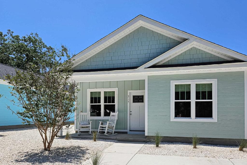 una casa azul con una silla en el porche en Pawsitive Island Escape, en Oak Island