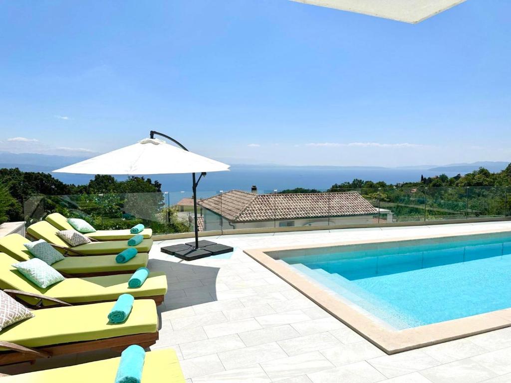 a swimming pool with lounge chairs and an umbrella at Villa Marta in Opatija