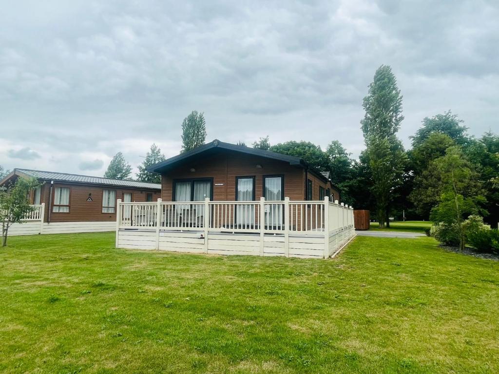 una casa con una valla blanca en un patio en Lakeside View Lodge with Hot Tub en York