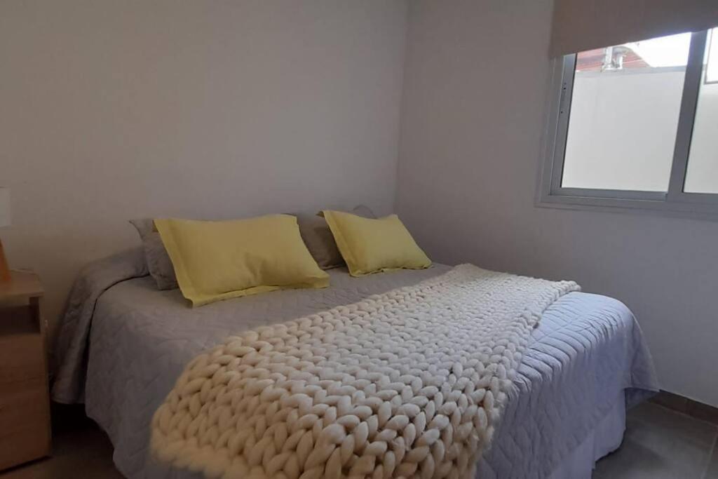 Un dormitorio con una cama con almohadas amarillas y una ventana en Excelente departamento muy bien ubicado en Mendoza