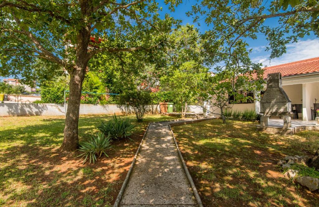 un jardin avec un arbre et un trottoir dans l'établissement Apartment Dinka, à Čižići