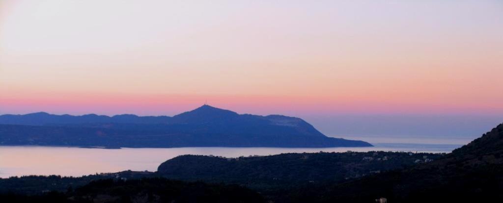 una puesta de sol sobre un lago con una montaña en la distancia en Villa Aspro en Xirostérnion
