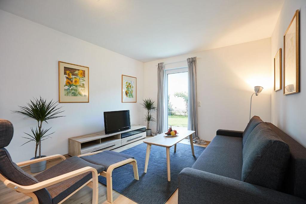 a living room with a blue couch and a tv at Ferienwohnung zum Steingarten in Krün