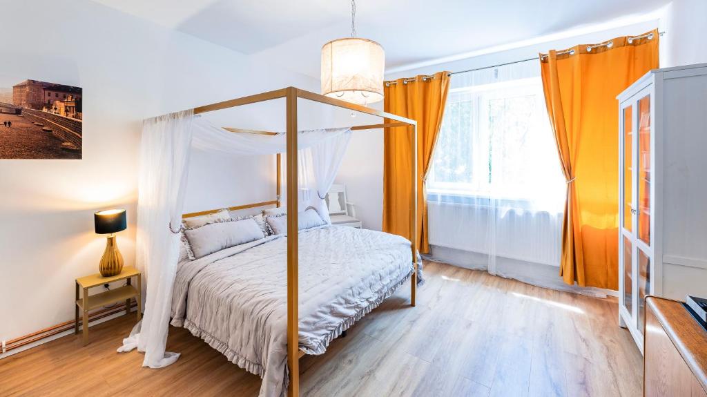 een slaapkamer met een hemelbed en oranje gordijnen bij Silvie Apartments - Masaryk dolní in Olomouc