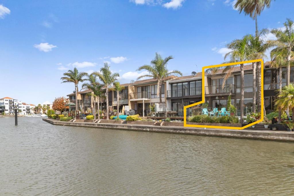 a building next to a river with palm trees at Absolute Waterfront Marina Views in Patterson Lakes