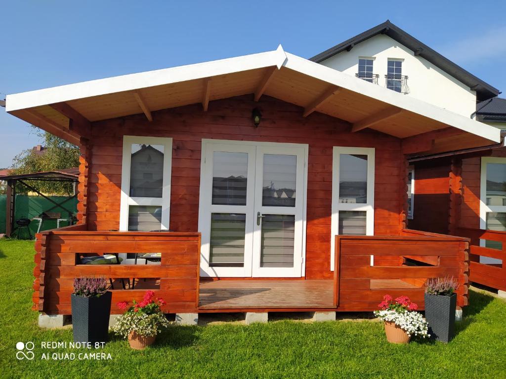 a small house with a porch and a deck at Domki Family Rowy in Rowy