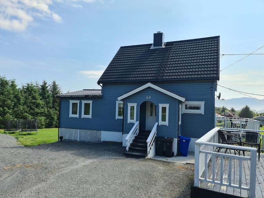 Cette petite maison bleue dispose d'une terrasse couverte et d'escaliers. dans l'établissement Koselig hus med hage i Herøy på Sunnmøre., 