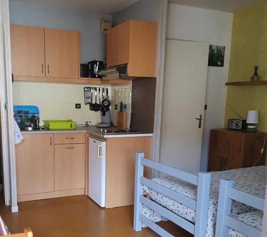une cuisine avec des armoires en bois et un réfrigérateur blanc dans l'établissement Studio 2 lits barbotan les thermes, à Cazaubon