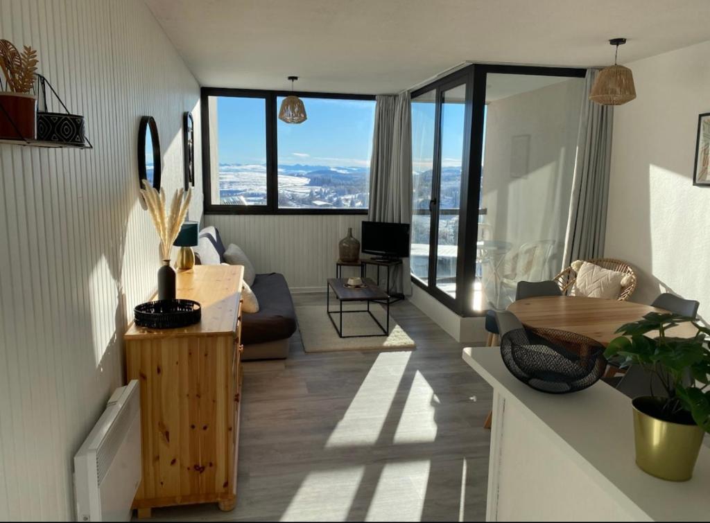 - un salon avec une table et quelques fenêtres dans l'établissement Appartement au cœur de la station de Super-Besse, à Besse-et-Saint-Anastaise