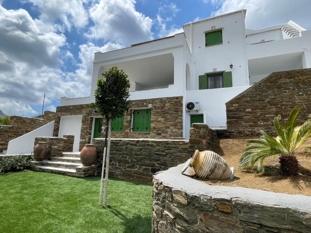 a white house with a stone wall at Komis Crown - Luxury Apartments in Kómi