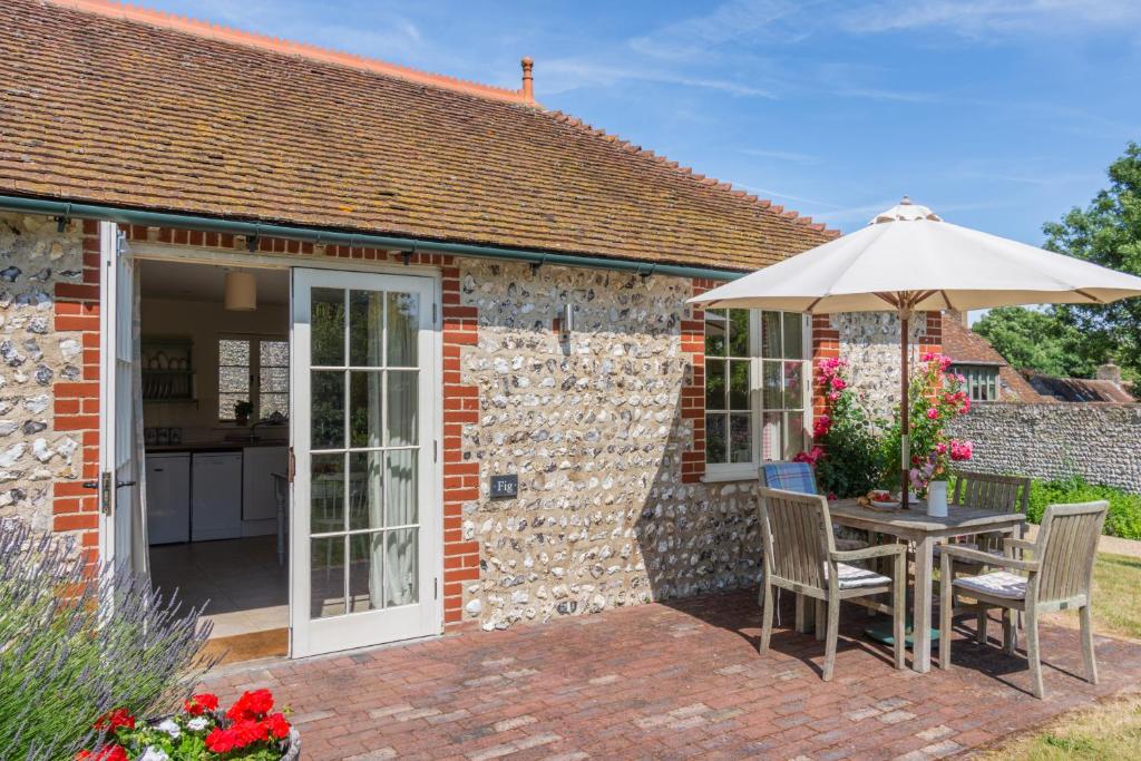 a patio with an umbrella and a table and chairs at Fig Cottage in Eastdean