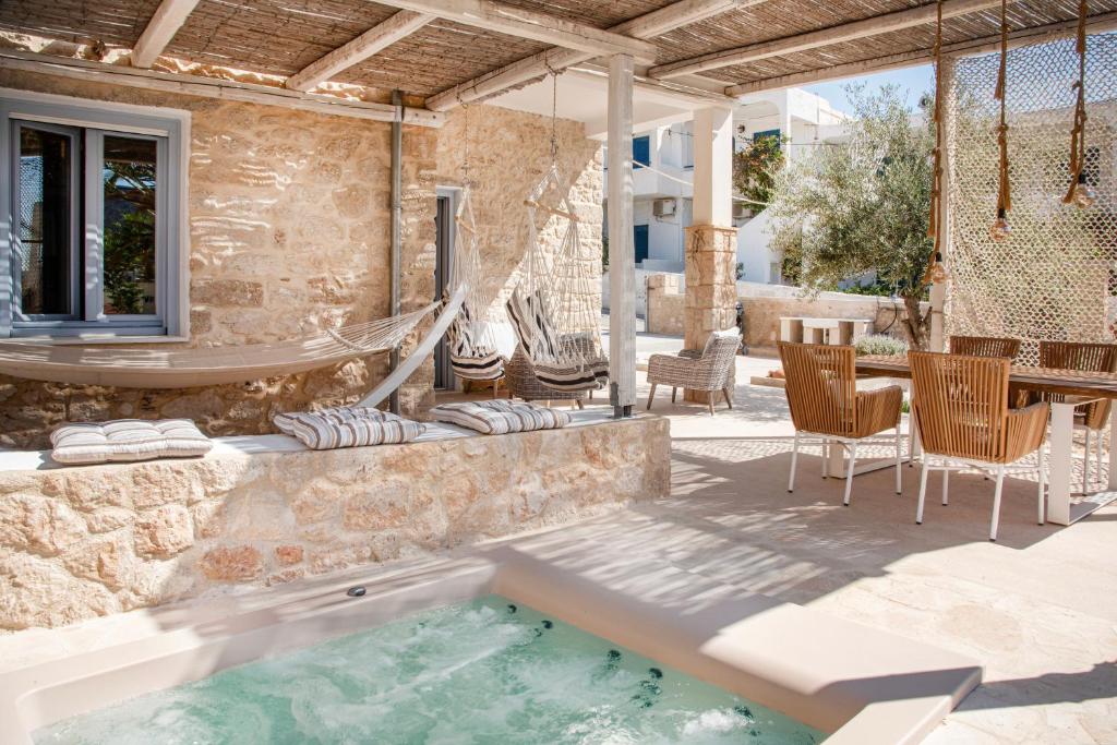 een patio met een zwembad en een tafel en stoelen bij TERRA E SOLE spa suite Aegina in Vathí