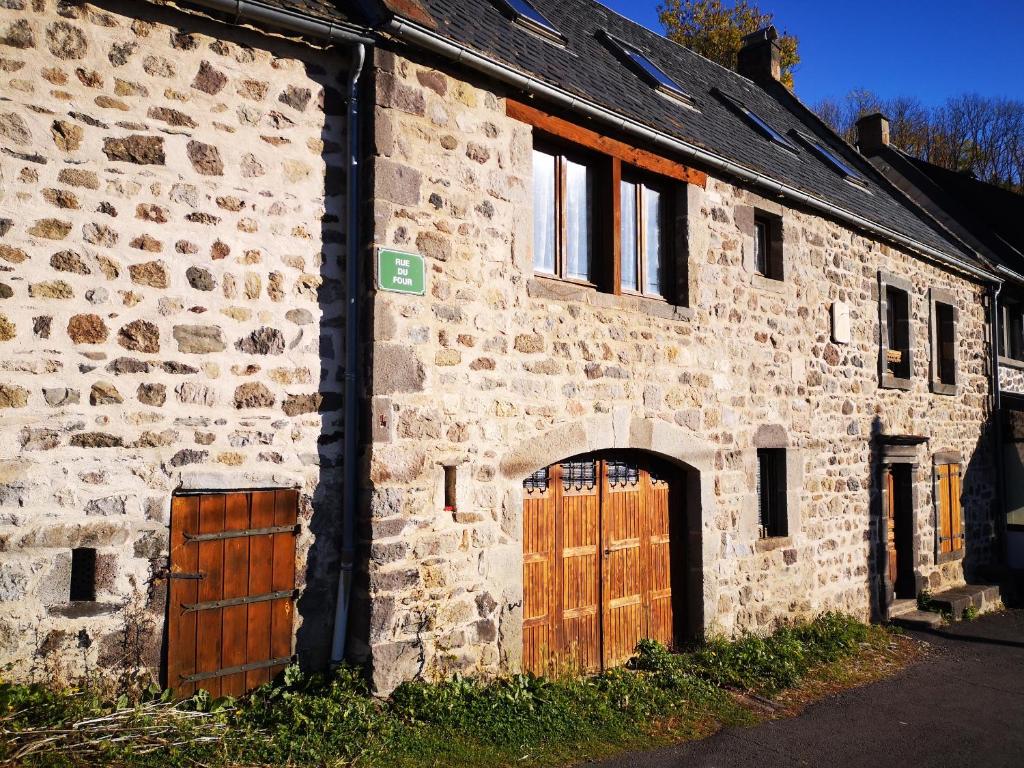 an old stone building with two wooden doors at Maison de Varennes in Chambon-sur-Lac