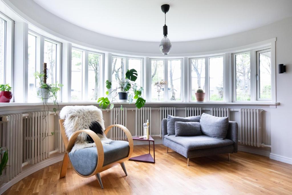 a living room with a couch and chairs and windows at Bright apartment near city center in Reykjavík