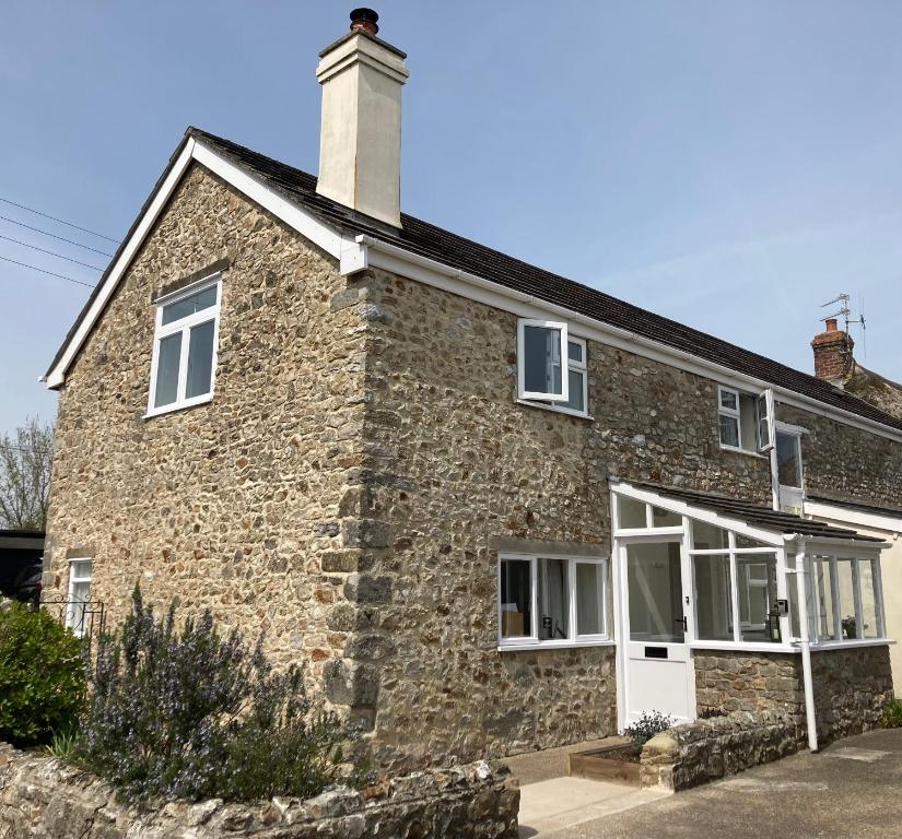 a brick house with white windows and a chimney at Ashes Farm Cottage in Kilmington