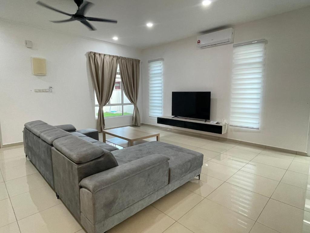 Una sala de estar con un sofá y un televisor de pantalla plana. en Casa Forest Homestay, en Keluang