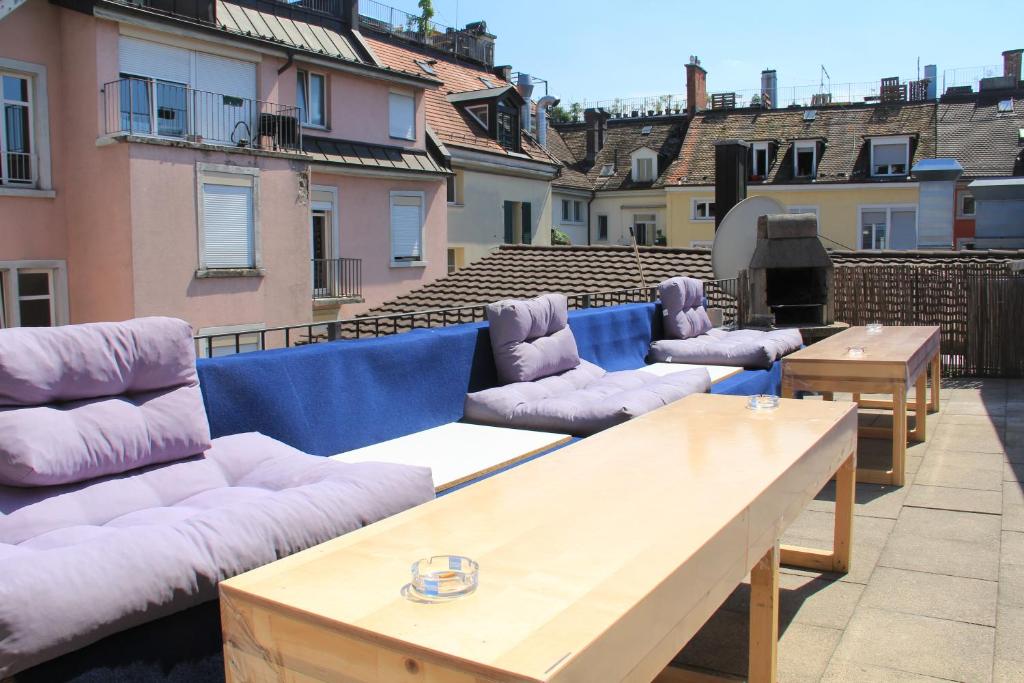 een rij banken en tafels op een balkon bij Stay2Night City Center Hostel in Zürich