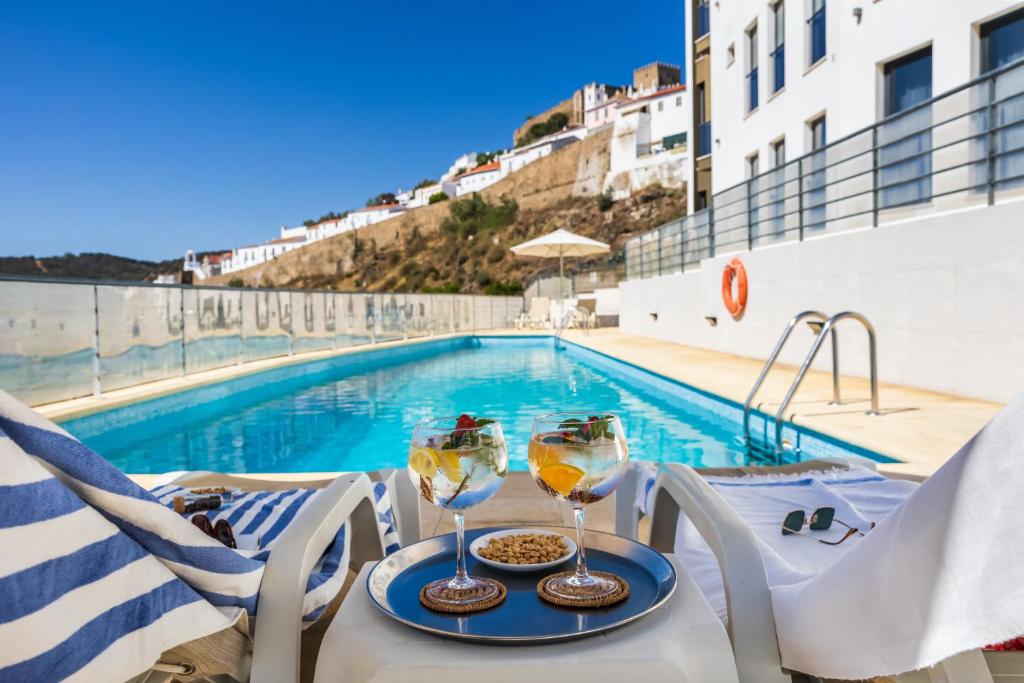 una mesa con dos copas de vino junto a una piscina en Hotel Museu, en Mértola