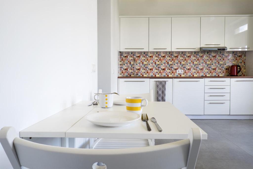 a white kitchen with a white table and chairs at Studio Świętojańska in Gdynia