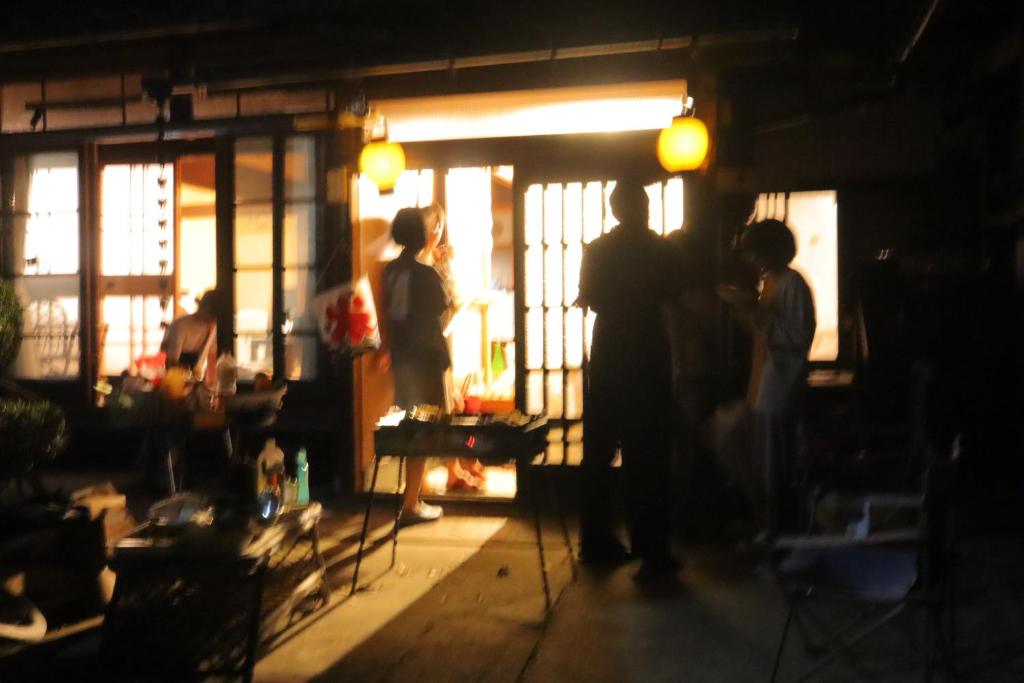 un grupo de personas de pie en una habitación oscura en ゲストハウス 瀬戸内ライフ, en Kure