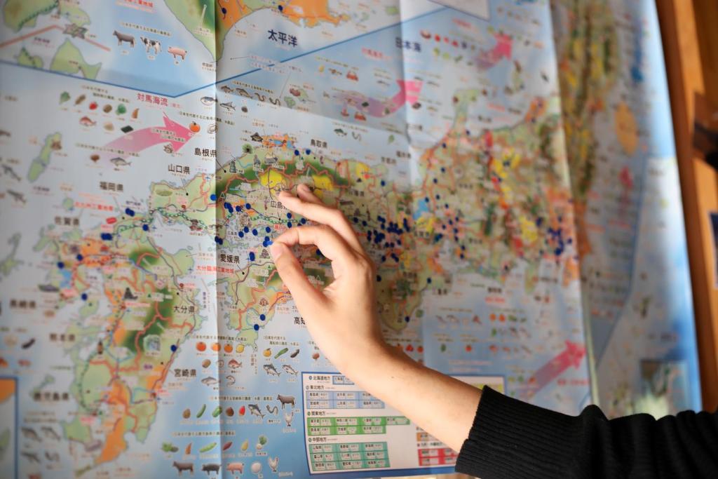 a person pointing to a map on a wall at Guesthouse SETOUCHI LIFE in Kure