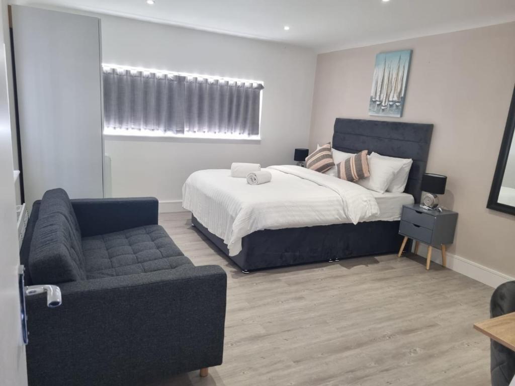 a bedroom with a bed and a couch and a chair at The Coppice-Private Studio Guest Suite With Private Entrance in Watford