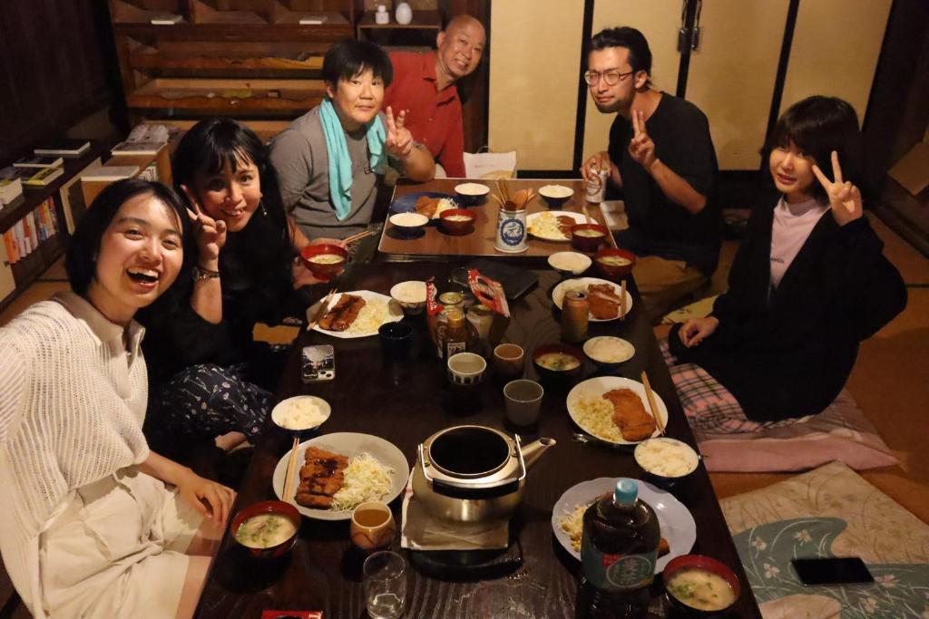 a group of people sitting around a table eating food at Guesthouse SETOUCHI LIFE in Kure