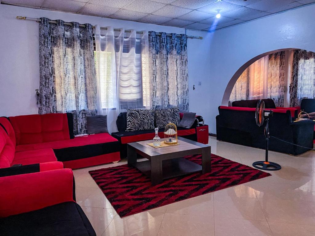 a living room with red couches and a coffee table at Tinas Royal Cottage in Mombasa