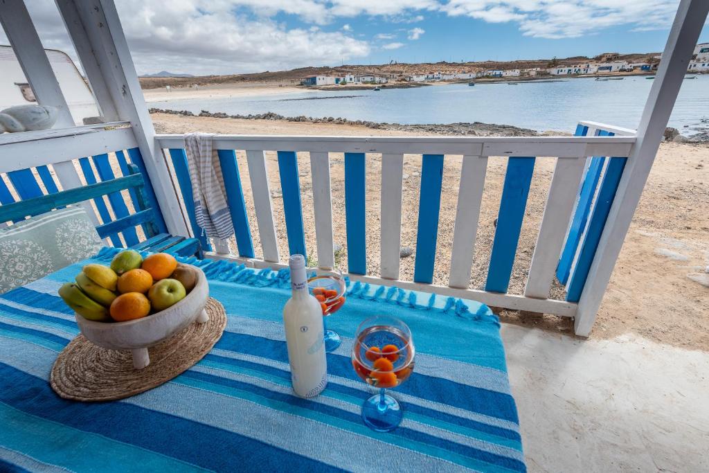 una mesa con un bol de fruta y una botella de vino en Cabin in front of idyllic majanicho beach, en Majanicho