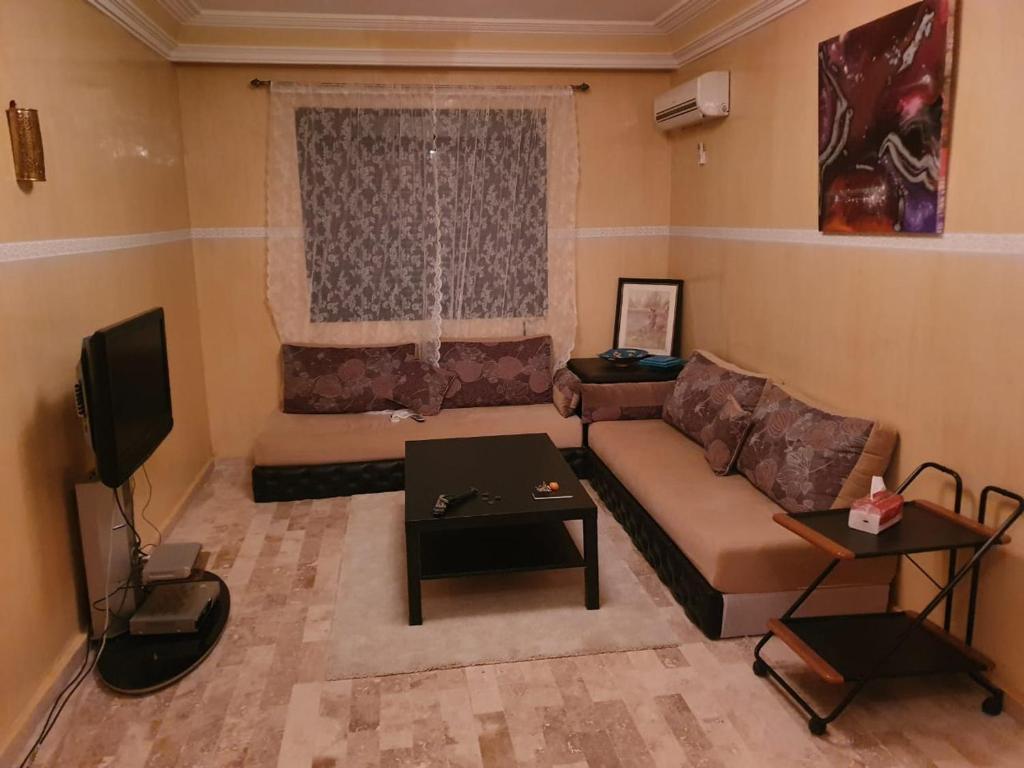 uma sala de estar com um sofá e uma televisão em Appartement rez-de-chaussee em Aït Ali