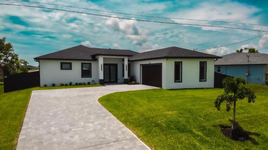 a house with a green lawn in front of it at Corallo House - Heated Pool in Cape Coral