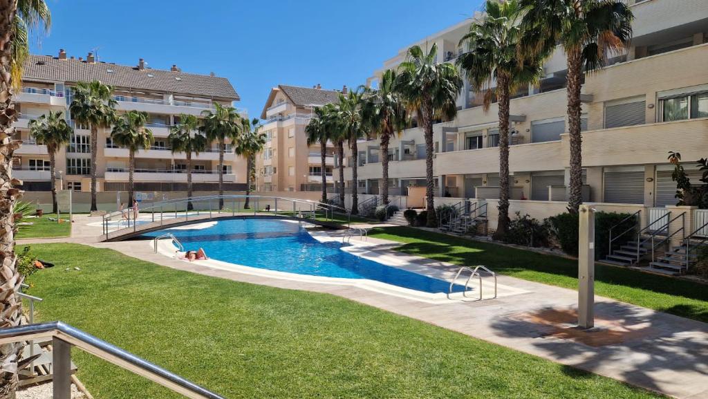 een zwembad voor een gebouw met palmbomen bij Apartamento Denia Elegance Las Marinas in Denia