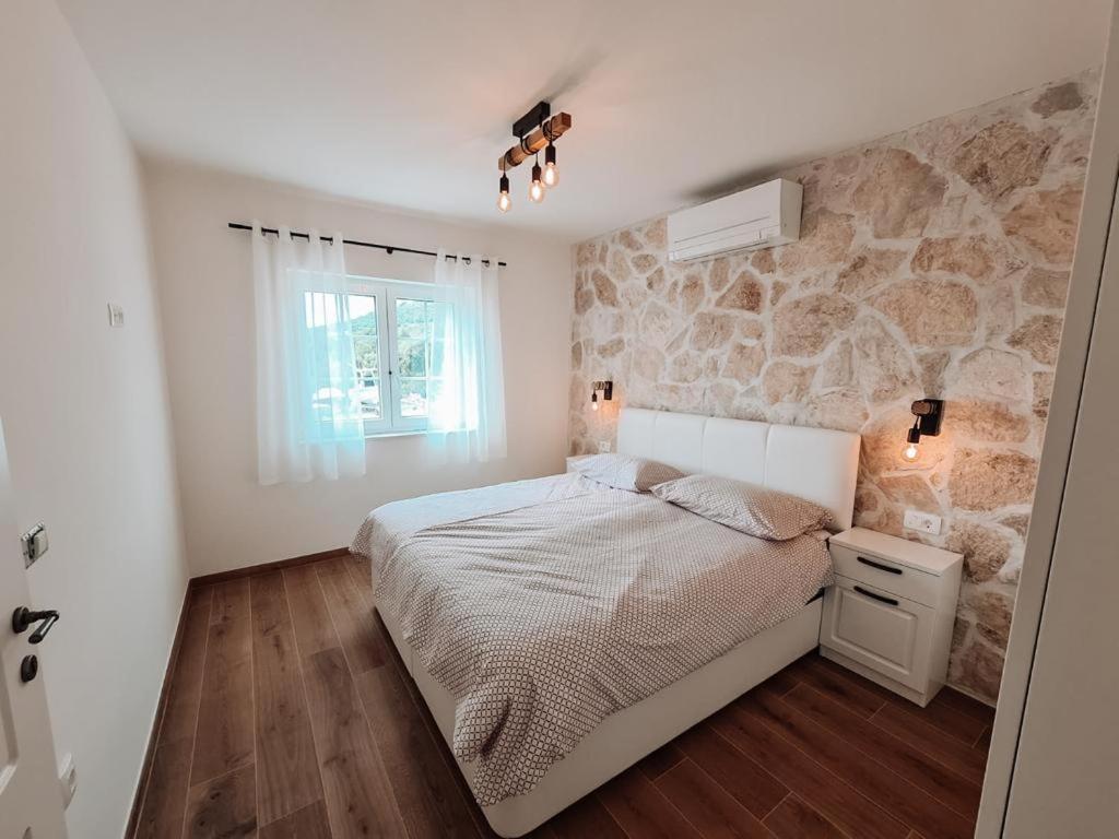 ein Schlafzimmer mit einem Bett und einer Steinwand in der Unterkunft STONE HOUSE JEZERA in Jezera