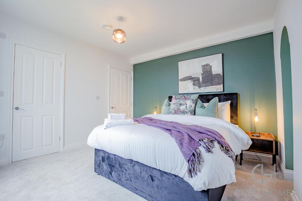 1 dormitorio con 1 cama grande y pared azul en Guest Homes - Foley House Apartments, en Great Malvern